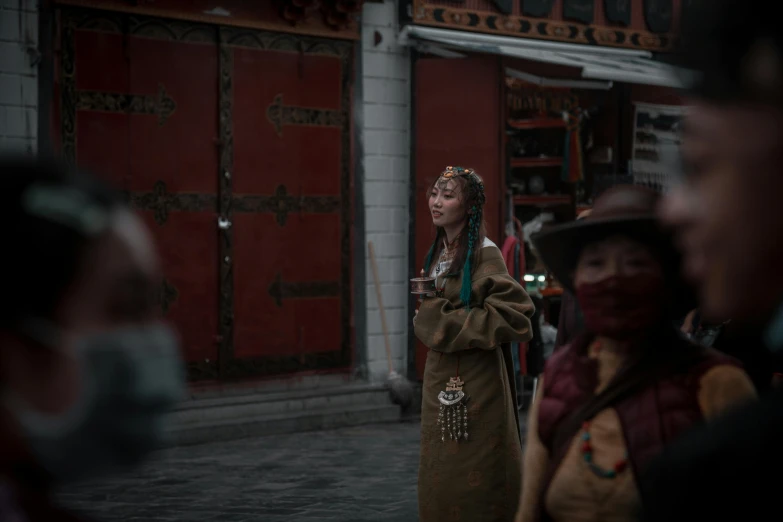 people in native clothes, two wearing face mask, one looking at cellphone