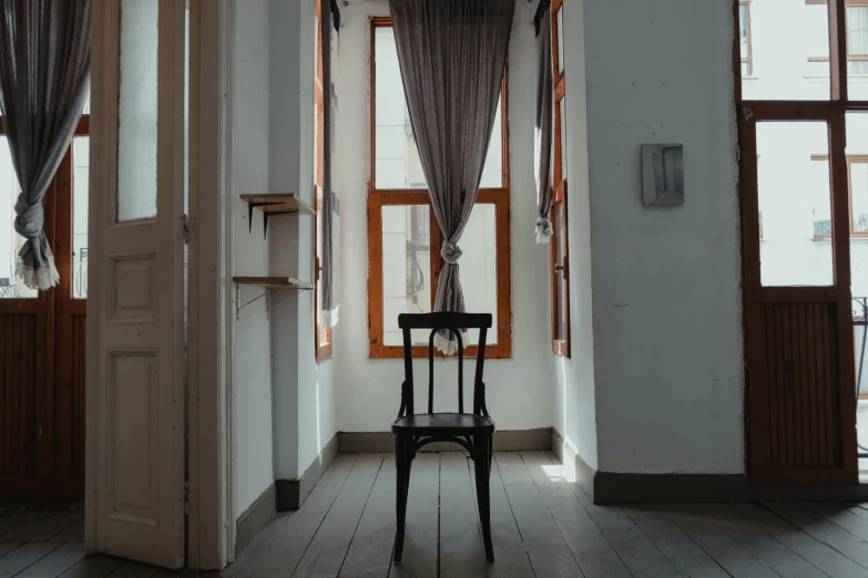 an empty chair sitting in a room between two windows