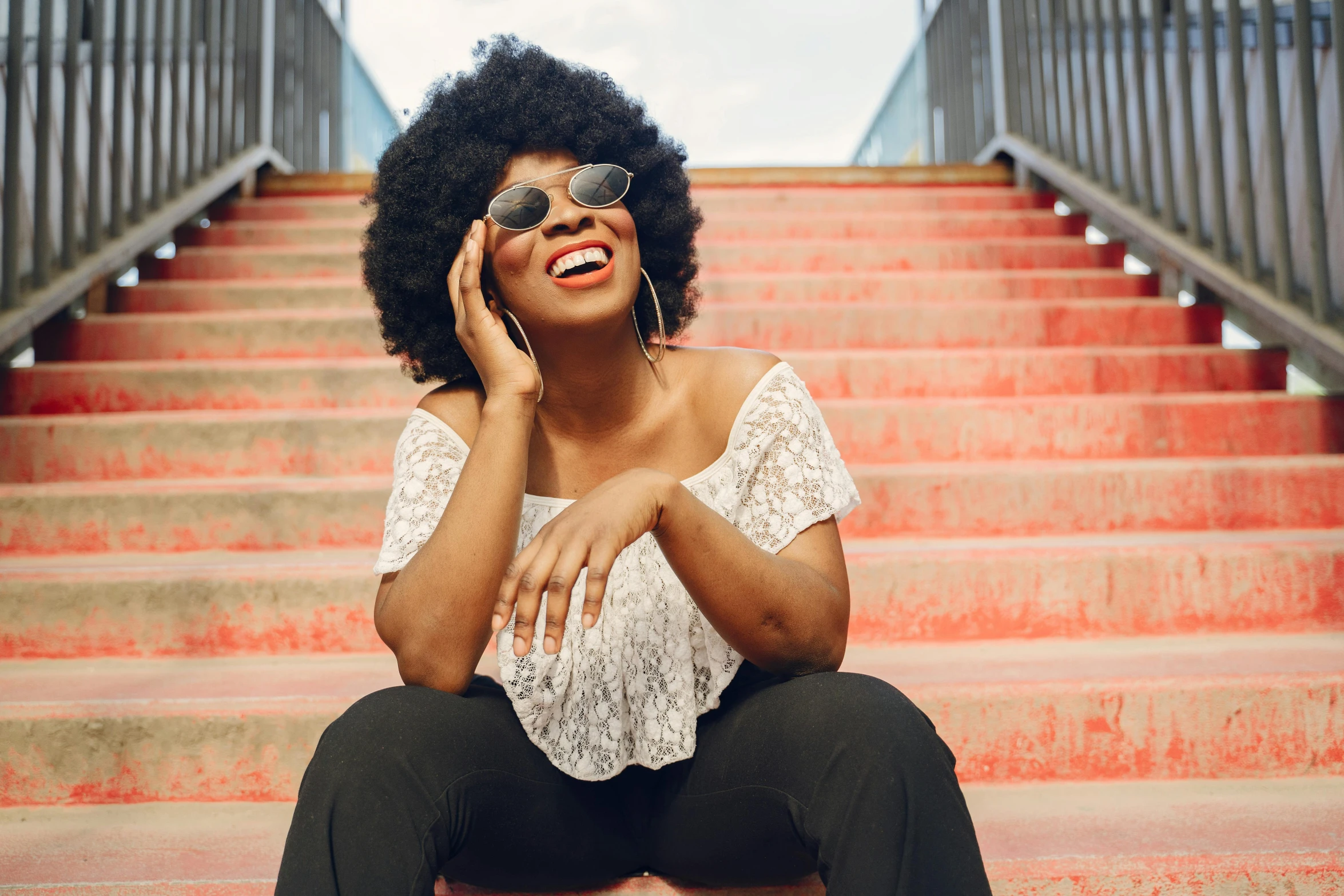 a woman sitting on a flight of steps while talking on a cell phone