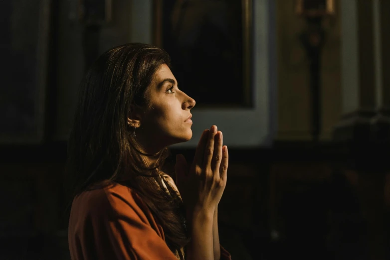 a woman in orange shirt and gold necklace clapping