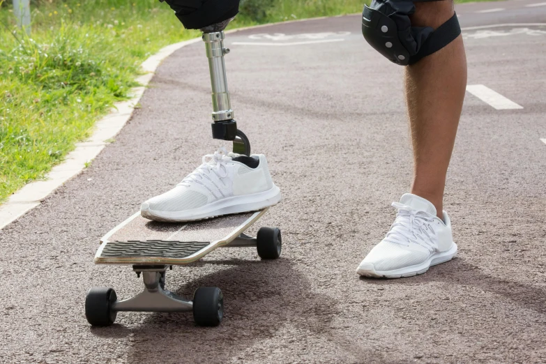 a person in white sneakers standing on skateboard on road