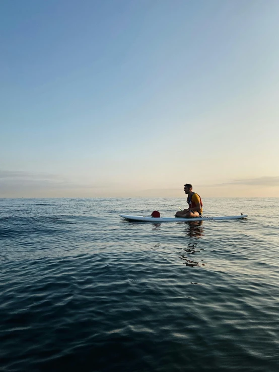 a man in the water on a surfboard paddling