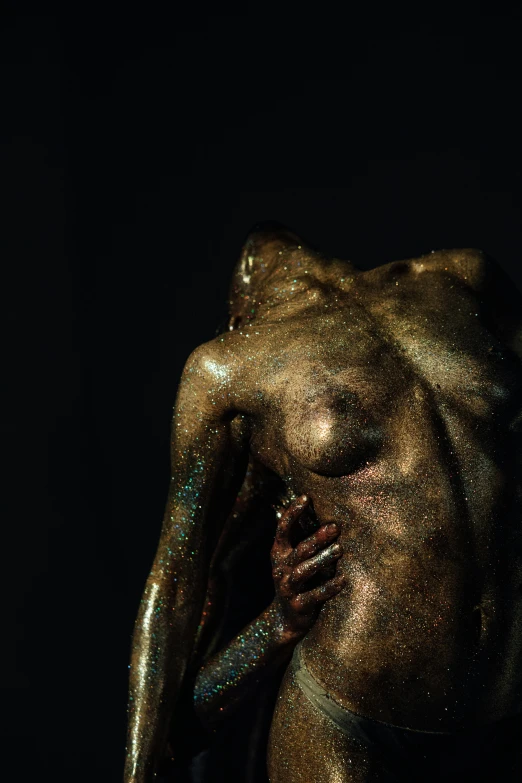 an image of a bronze person covered in gold liquid