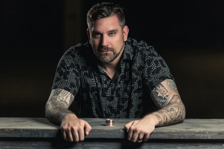 a man with some tattoos on his arm sits at a table