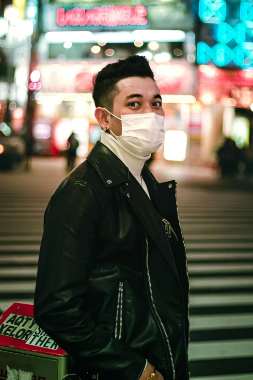 a man standing at the intersection wearing a mask