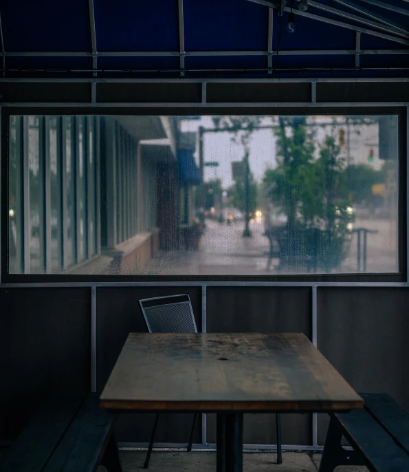 an outdoor restaurant table is seen through the rain window