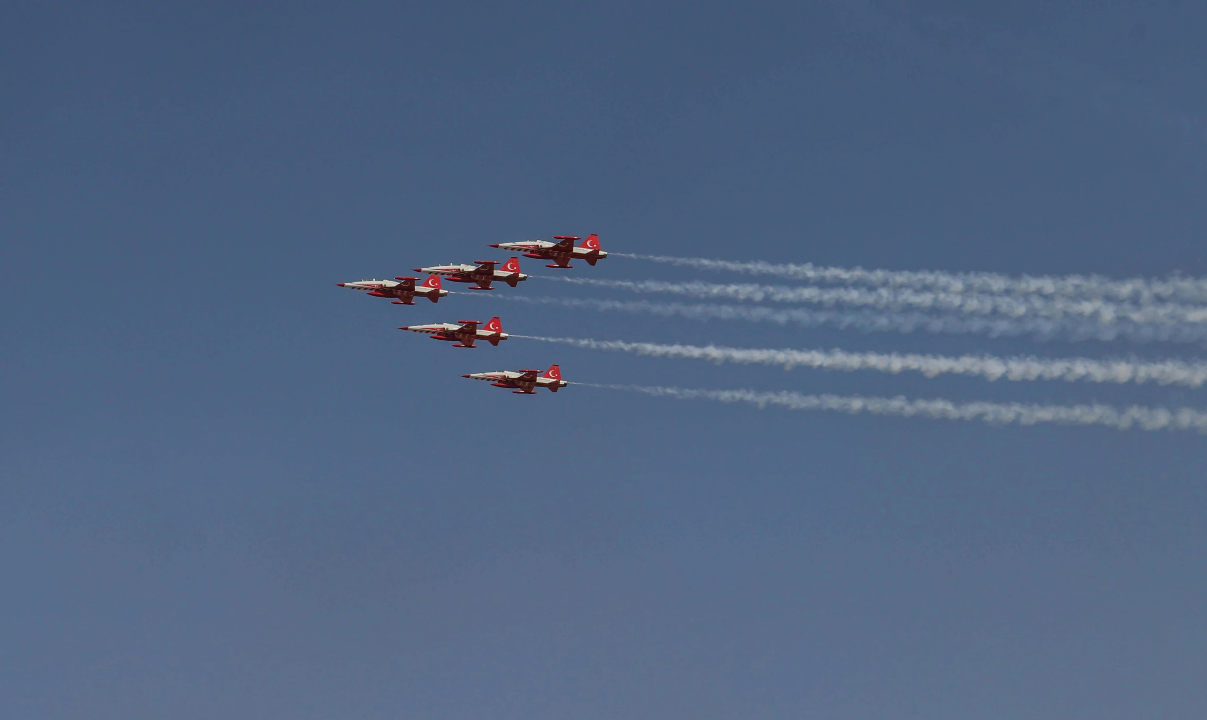 a group of four airplanes flying through a blue sky