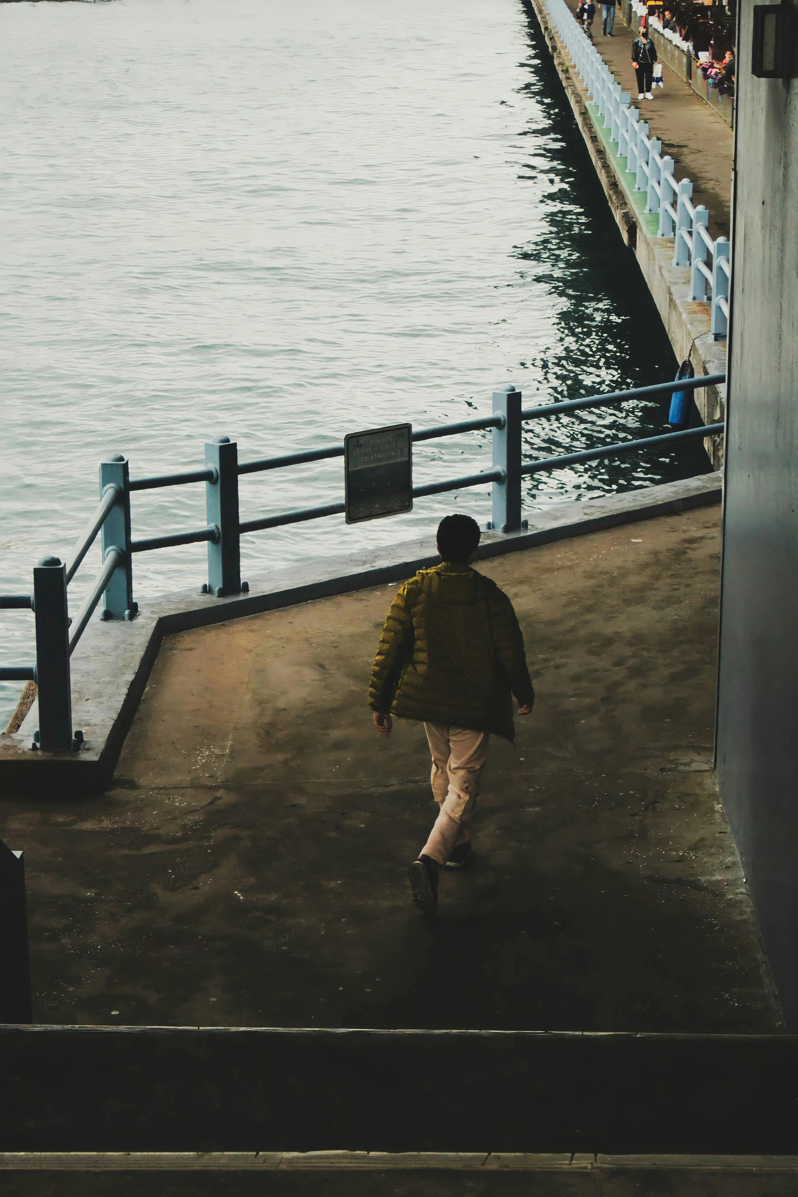 a person in an orange jacket is walking away from the ocean