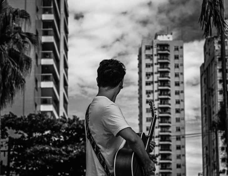 a man holding a guitar and some buildings