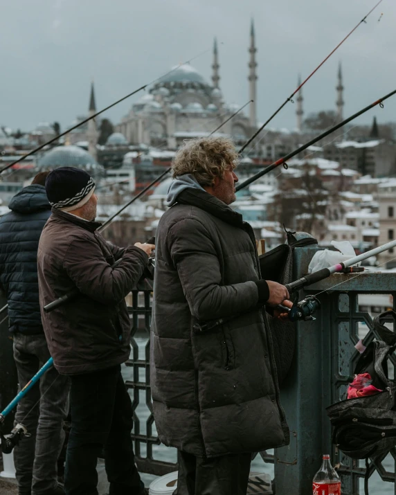 two people who are standing on a bridge fishing