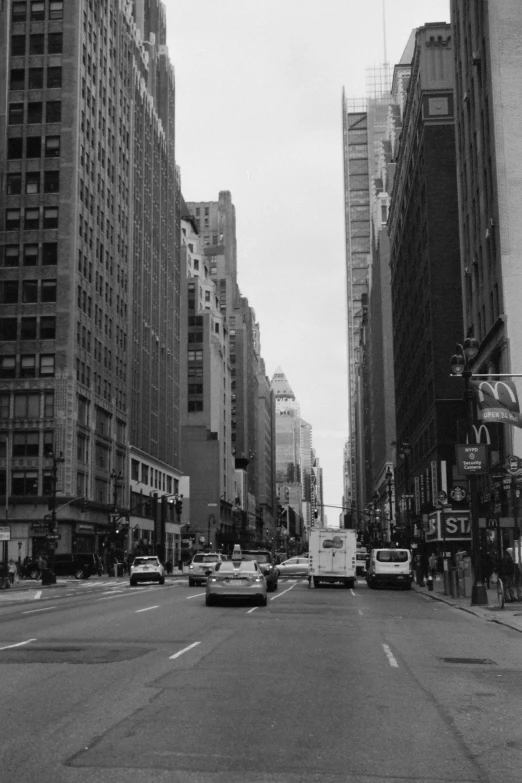 cars are driving down an urban street with tall buildings