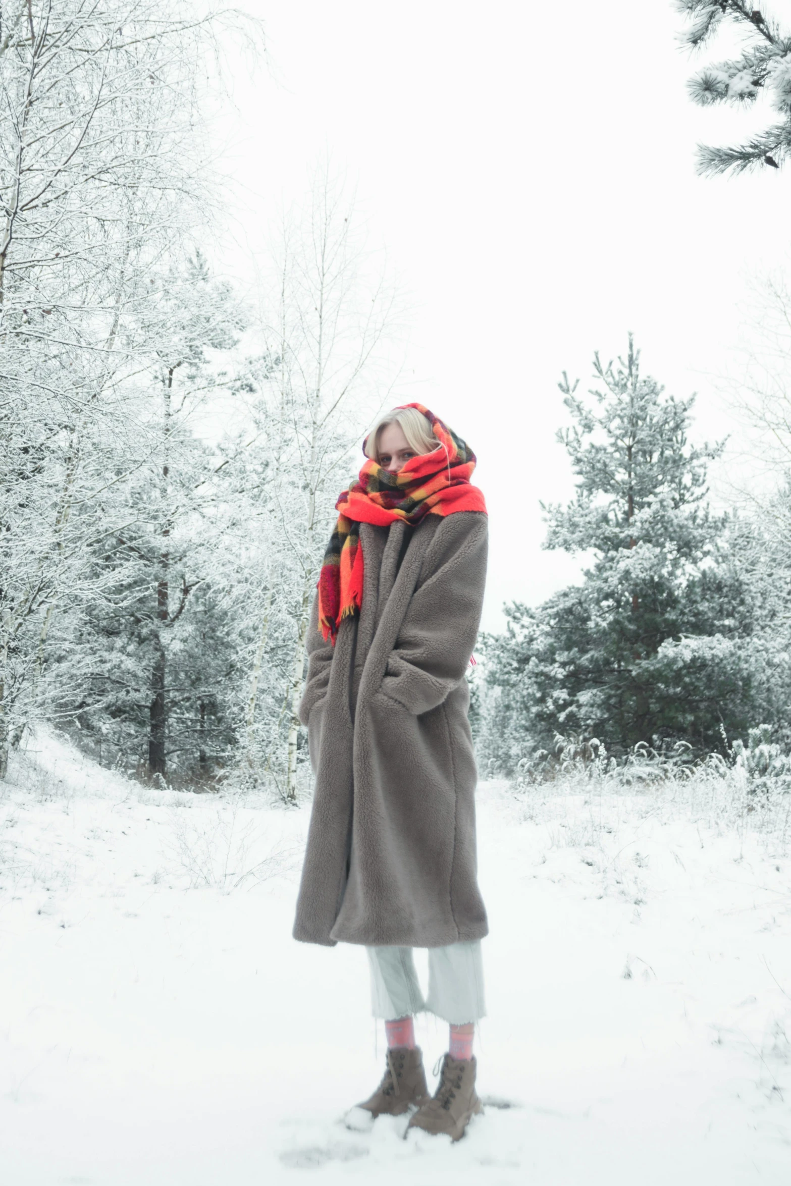 a woman stands in the snow in a long coat