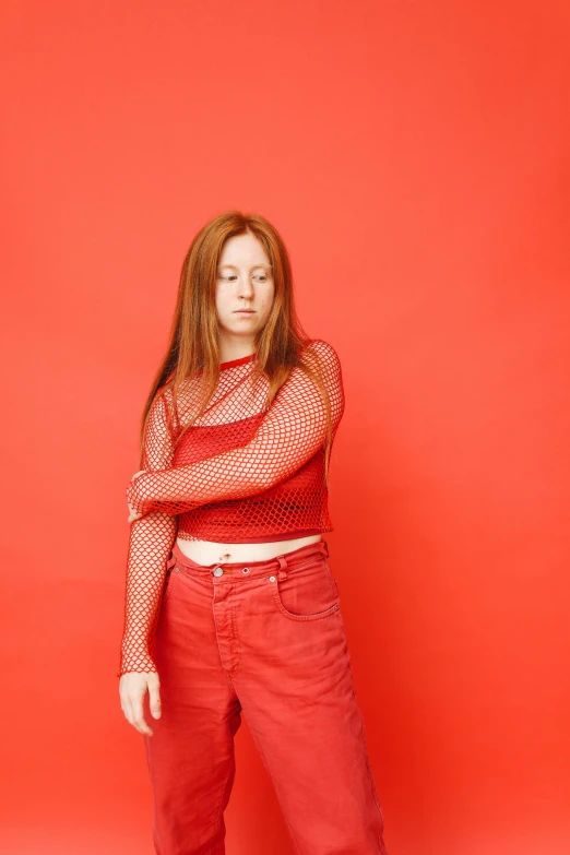 a woman is standing against a red wall