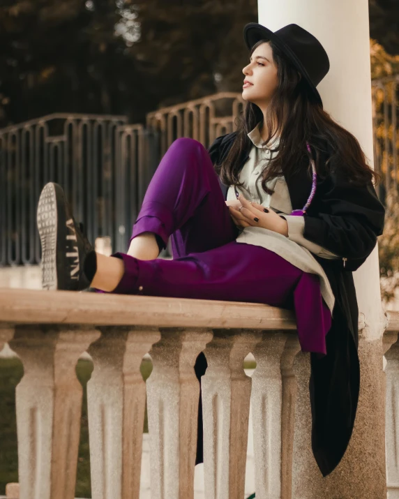 a beautiful woman in black hat sitting on the outside balcony