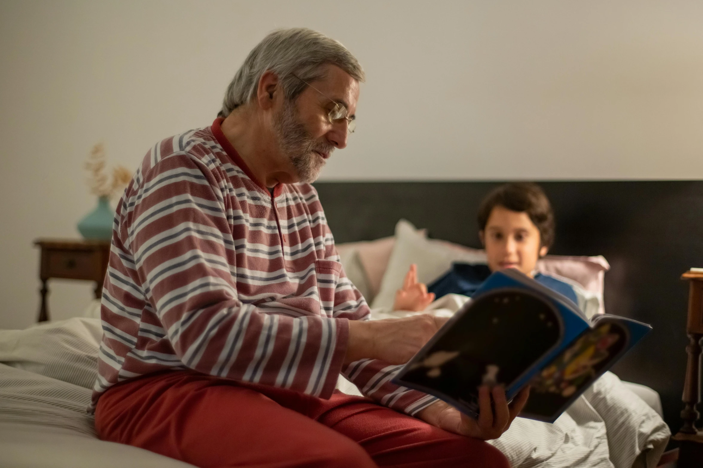 an old man reading a book on his bed