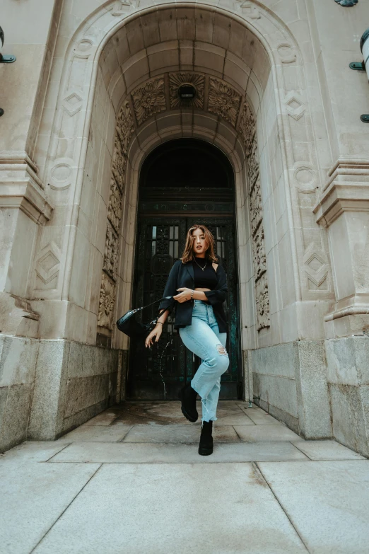 a woman in high heeled boots poses in front of an old building