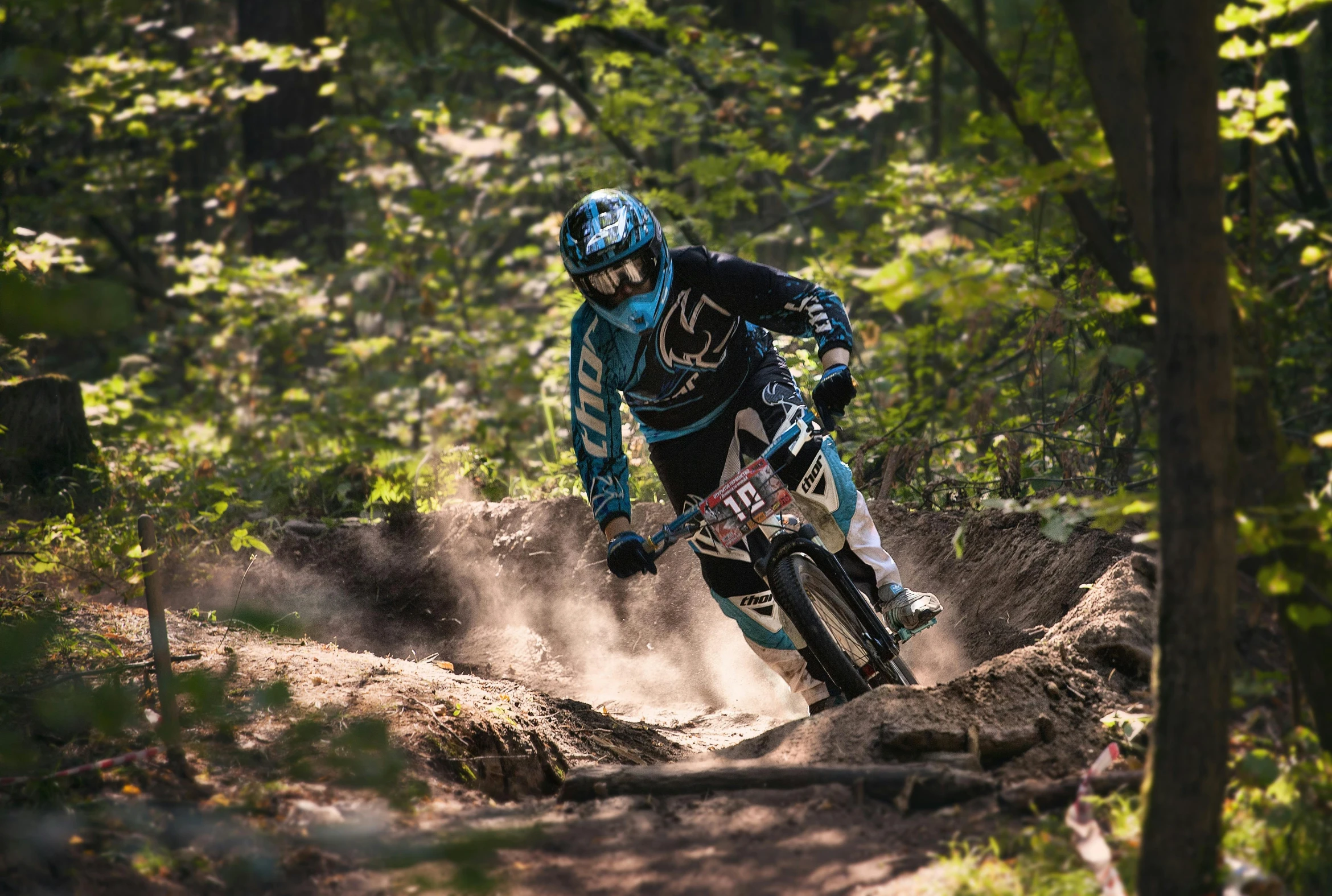 a man on a motorcycle rides over a trail in the woods