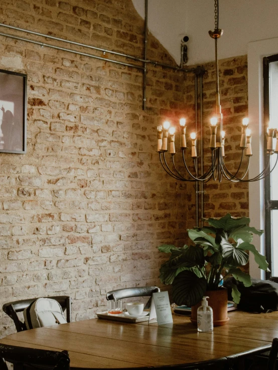 a dinning table set for two sits in front of a window and a brick wall