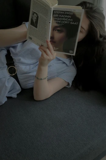 a person laying on a couch reading a magazine
