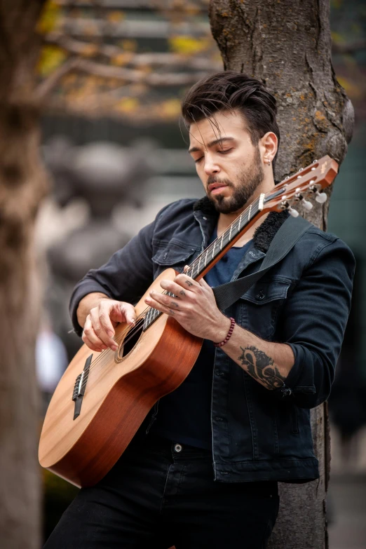 a man with long hair playing a guitar on the street