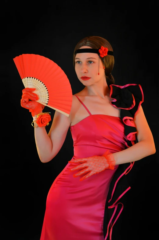 a woman in a pink dress holds a red and black fan