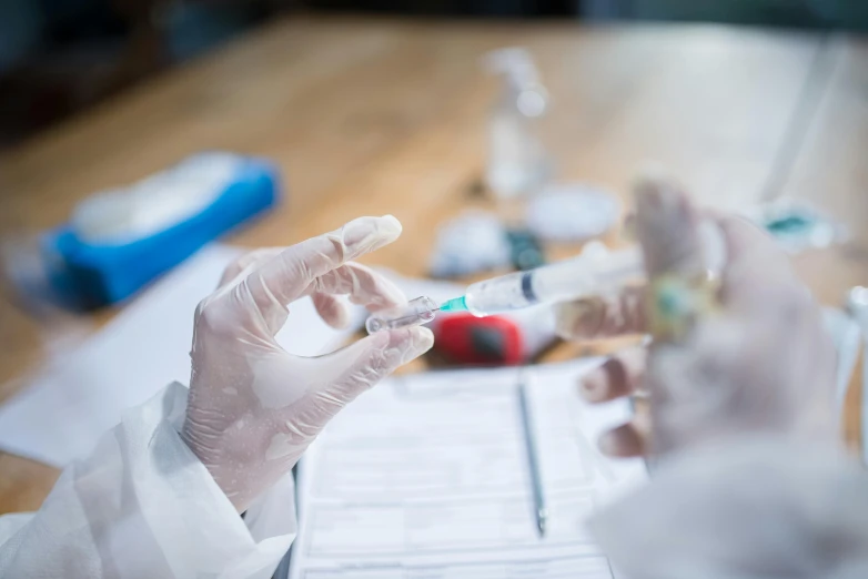 two people in white lab coats using vials on a piece of paper