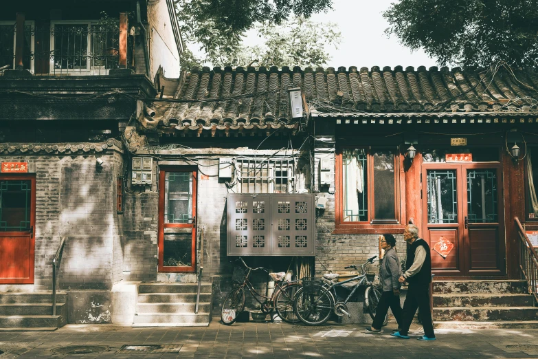 two men standing in front of an old building next to a bicycle