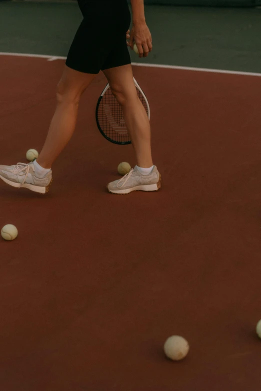 a woman holding a tennis racquet over four balls