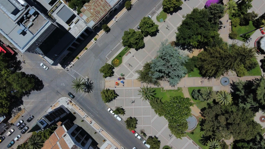 an aerial view of a town square with vehicles parked and a small building