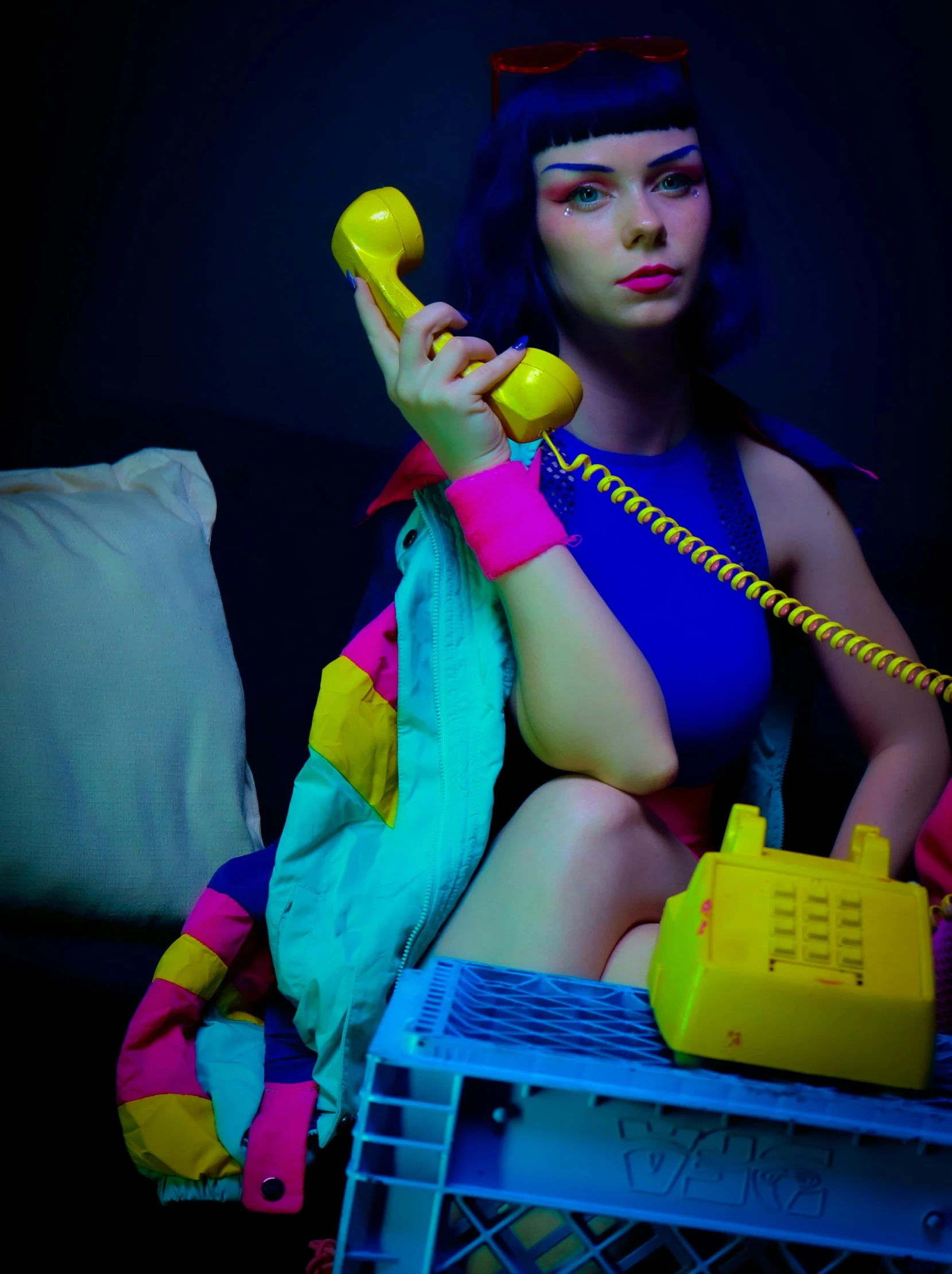 a woman in a blue bathing suit sits next to a yellow telephone