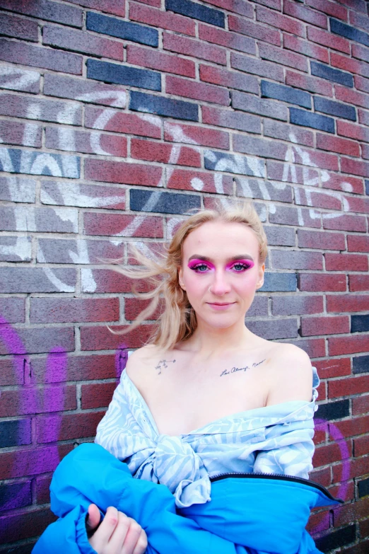 a girl standing in front of a brick wall