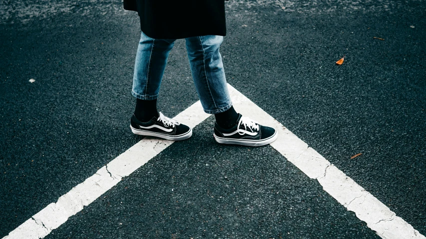 a person wearing converse shoes while crossing the street