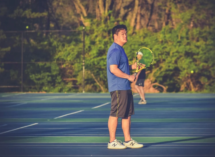 a man in a blue shirt stands on a tennis court