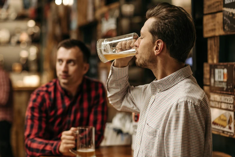 a man drinking from a bottle over another man's shoulder