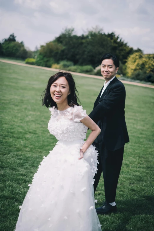 a man and woman wearing a suit standing in grass