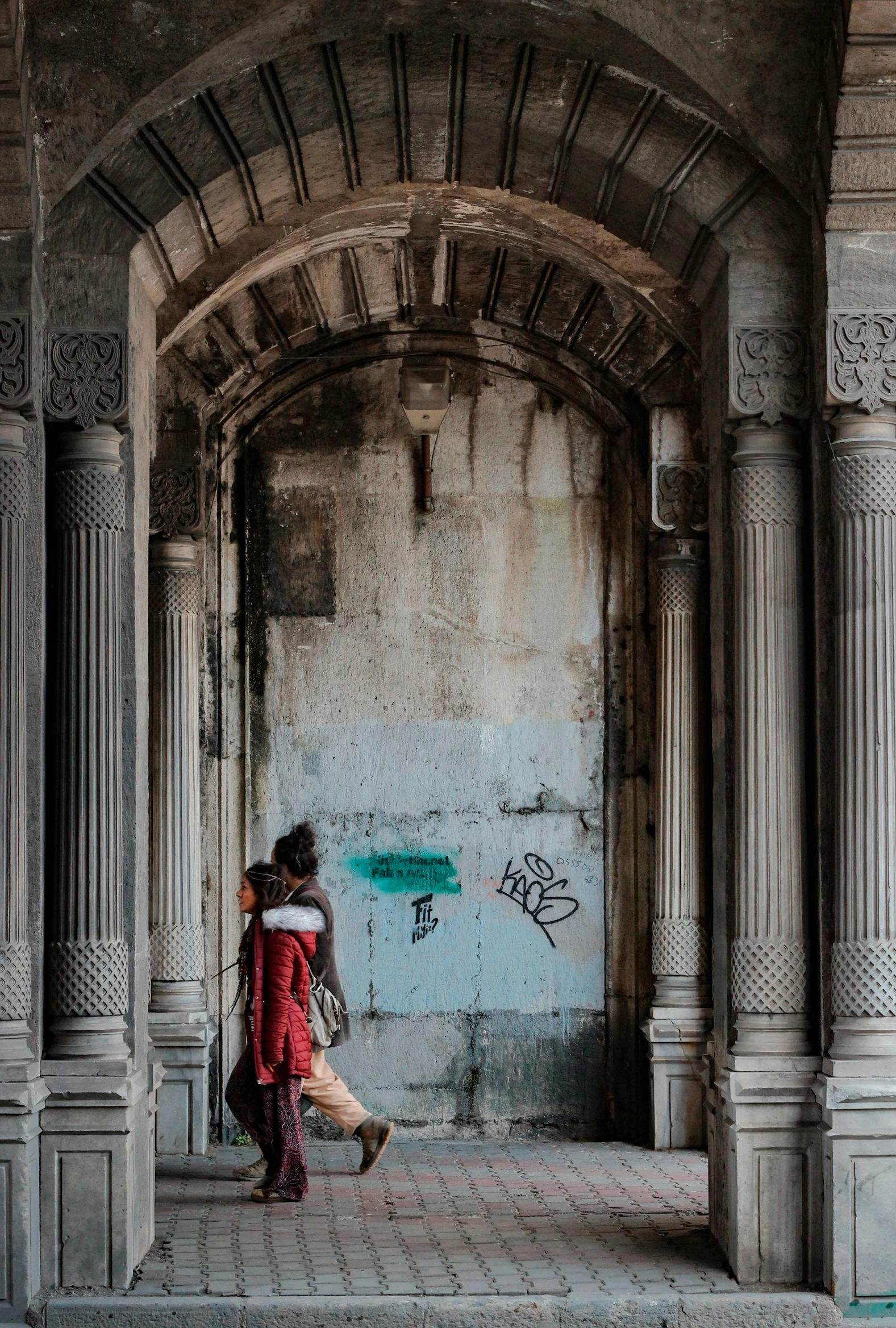 a couple of people are walking underneath a arch