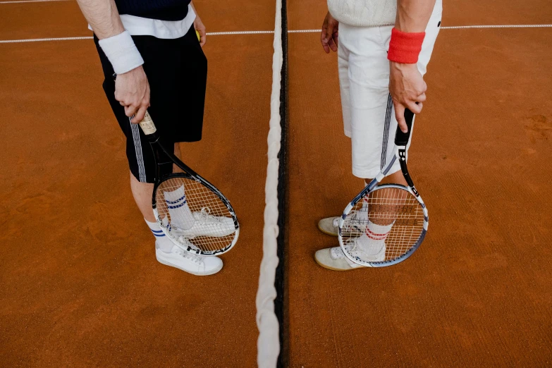 two people standing on tennis court with rackets in their hands