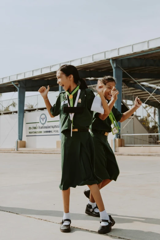 two girls dressed in military uniforms walk on the cement