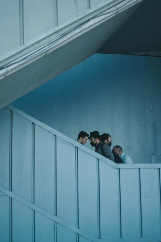 several people are sitting outside looking over a railing