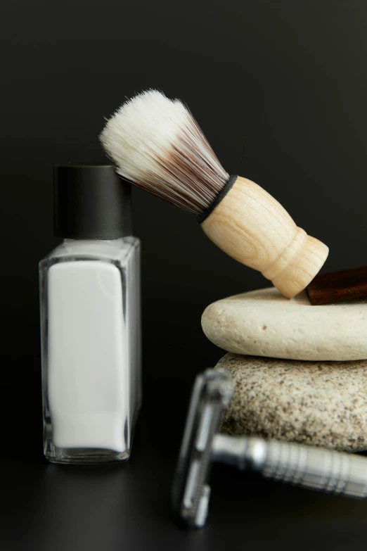 a close up of a brush and soap on top of stone