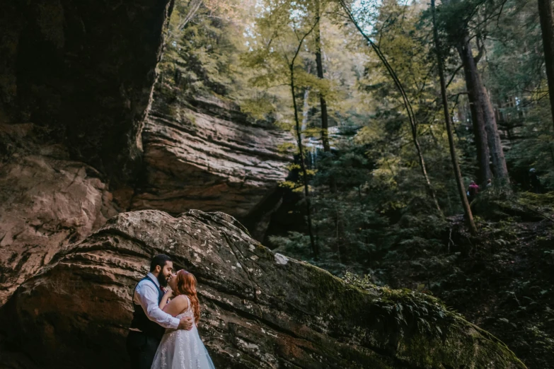 a couple on their wedding day are standing in the middle of a forest