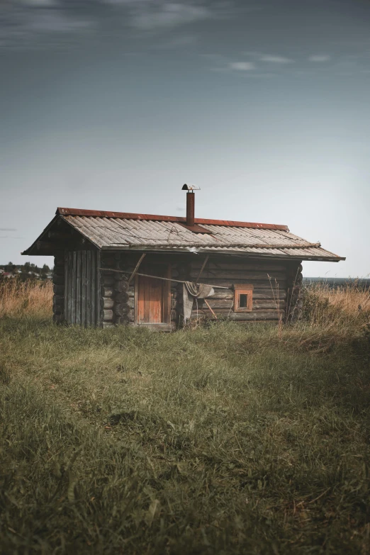an old wooden cabin sitting in the grass