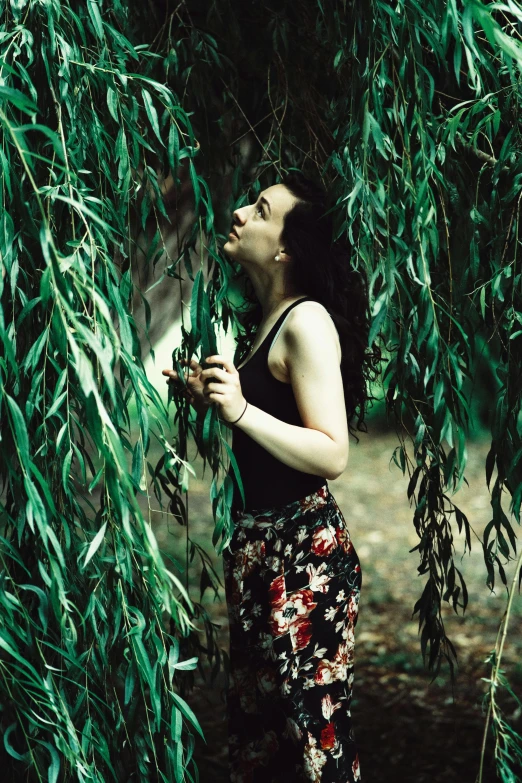 a woman is looking up and standing under a tree