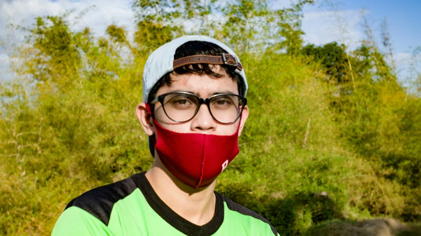 man with a red face mask, glasses and a green shirt