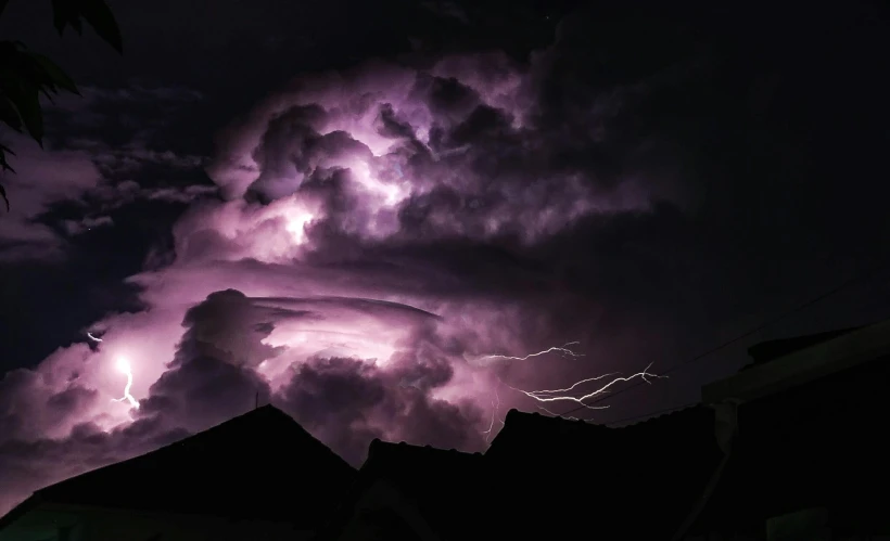 a lightning storm is seen over the roof of a home