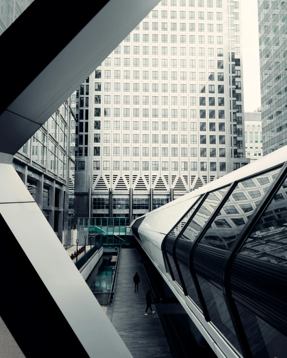 looking down on the top of an escalator in a high - rise area with people walking up to the train station