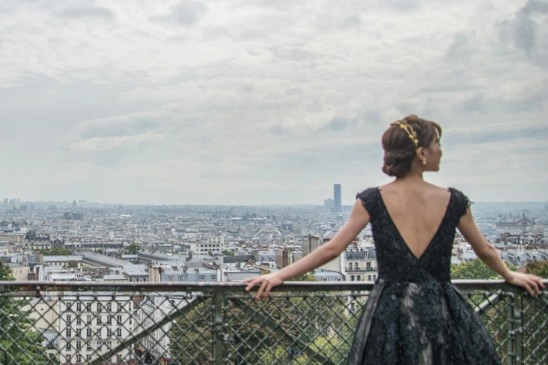 the back view of a woman standing on a fence