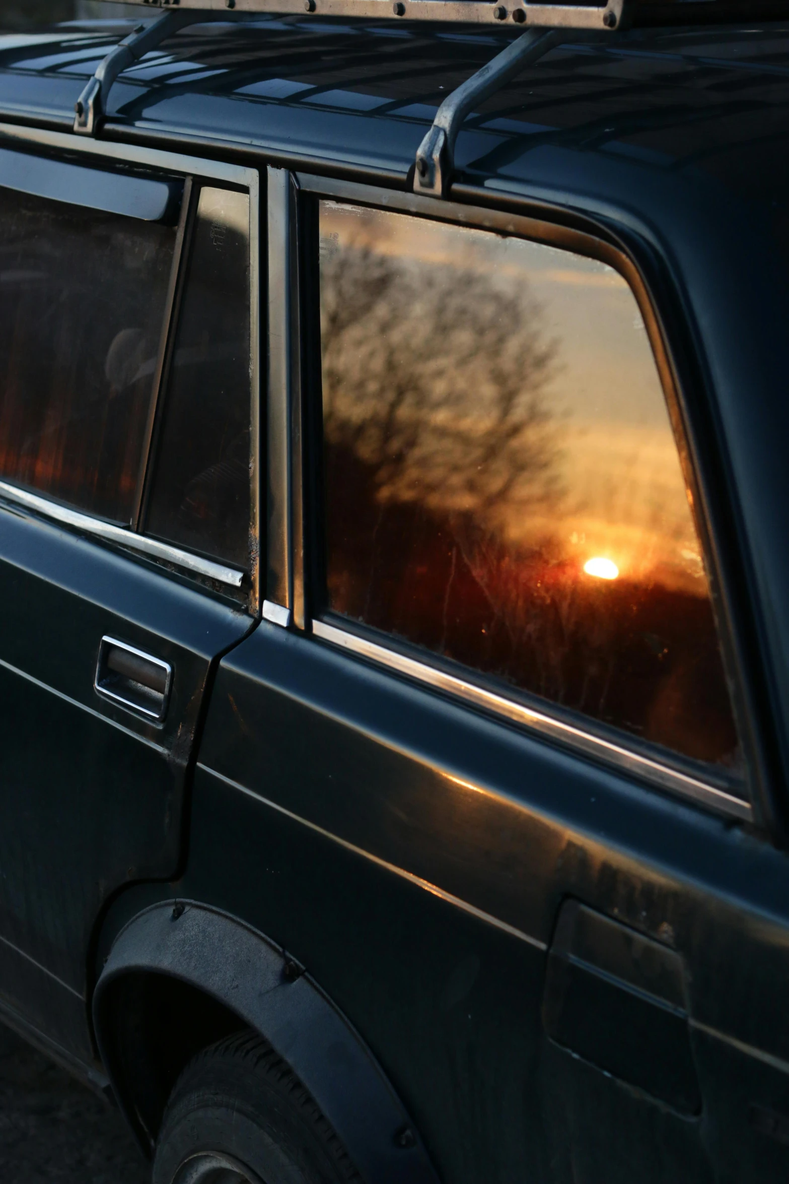 the sun is setting through the trees and reflecting in a window