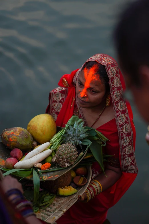 the woman is holding several fresh fruit and vegetables