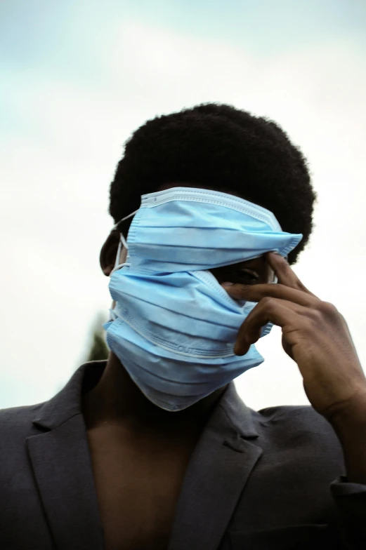 man with blue mask and black hair covers his face